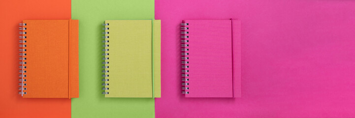 Banner with colorful notebooks on orange, green and pink background. Back to school banner. - Powered by Adobe