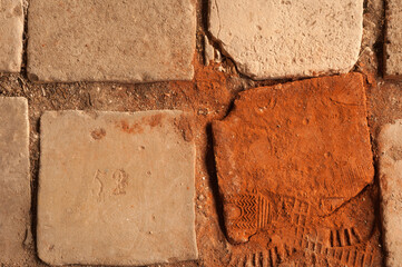 Huellas de calzado en un antiguo suelo de losas de barro.