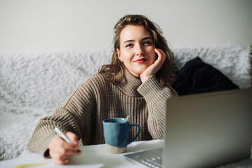 A female PR manager creates an online store content plan from home, working at the kitchen table...