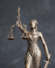 themis is goddess of justice statuette on dark background. symbol of law with scales and sword in...