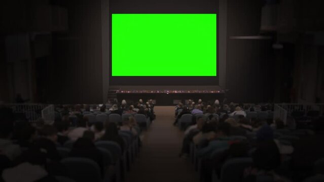 Crowd of people watch big green screen