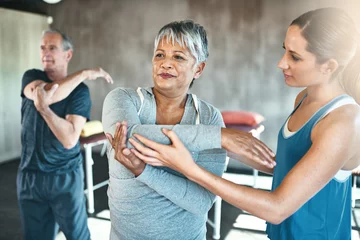 Gordijnen Stretching, physiotherapy and old woman with personal trainer for fitness, wellness or rehabilitation. Health, workout or retirement with senior patient and female trainer in gym for warm up training © Mikolette M/peopleimages.com