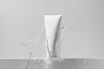 White mockup tube of cream with splash of water on isolated background. The concept of cosmetology,...