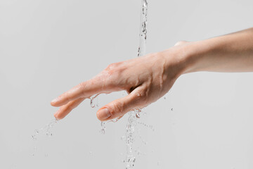 Female hand under a stream of water on a white isolated background. Concept of moisturizing...