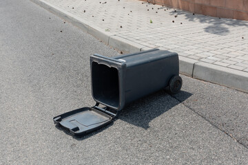Plastic trash can container fell fallen on ground road