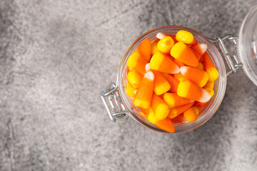 Halloween candy corn with pumpkin flavor and dragees on a black background. Classic sweet Halloween treats. Halloween holiday concept and Jack lantern.Place for text. Place to copy.