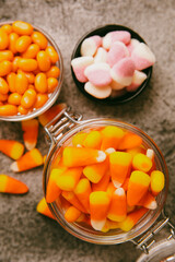 Halloween candy corn with pumpkin flavor and dragees on a black background. Classic sweet Halloween treats. Halloween holiday concept and Jack lantern.Place for text. Place to copy.