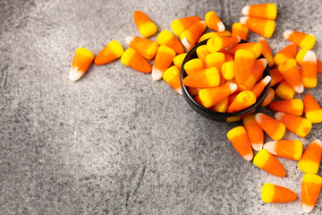 Halloween candy corn with pumpkin flavor and dragees on a black background. Classic sweet Halloween...