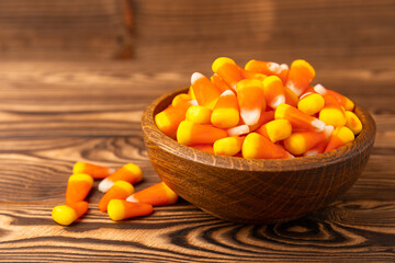 Halloween candy corn with pumpkin flavor and dragees on a brown background. Classic sweet Halloween treats. Halloween holiday concept and Jack lantern.Place for text. Place to copy.