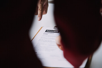 Businessman or job seeker review his resume on his desk before send to finding a new job with pen, necktie, glasses and digital tablet.