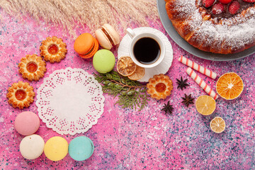 Fototapeta na wymiar top view delicious strawberry cake with french macarons and cup of tea on light-pink background cake sweet sugar cookie tea