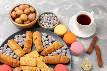 top view delicious sweet bagels with candies crackers macarons and cup of tea on white desk biscuit cookie sugar sweet