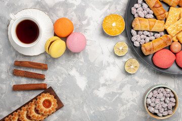 top view delicious sweet bagels with crackers cookies macarons and cup of tea on light white desk biscuit cookies sugar sweet pie