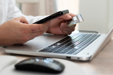 Fototapeta premium Businessman using their cell phone to online shopping with their credit card in his hand over the laptop