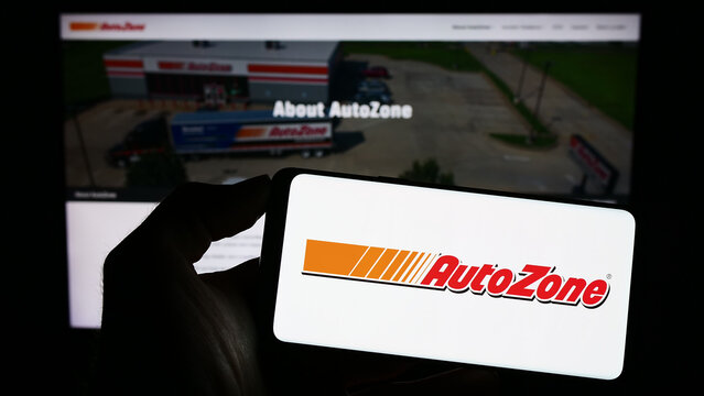 Stuttgart, Germany - 04-28-2023: Person holding smartphone with logo of US automotive parts company AutoZone Inc. on screen in front of website. Focus on phone display.