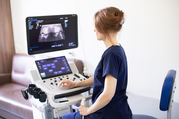 Doctor woman doing ultrasound scanning diagnostic of thyroid gland sitting in office in clinic.