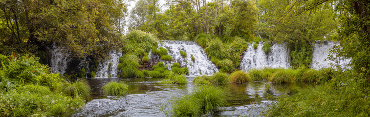 Fototapeta na wymiar Panoramic landscape view of the Arenteiro waterfalls in Ourense, surrounded by green grasses in summer 2021 Spain