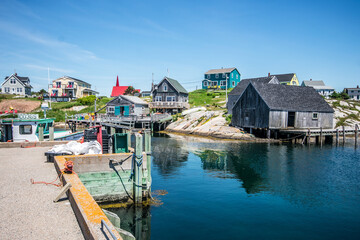 A boat docked in the bay of a fishing village at Peggy's Cove, Nova Scotia. - obrazy, fototapety, plakaty