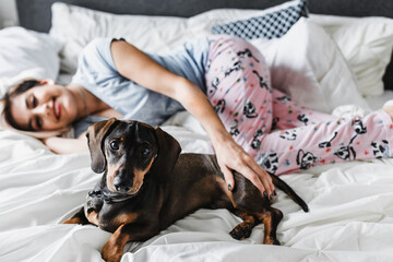 latin young woman with dog dachshund pet on bed at home in Mexico Latin America, hispanic female 
