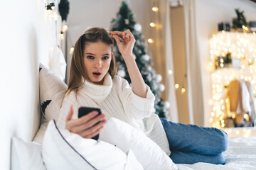 Shocked woman using smartphone during Christmas holidays