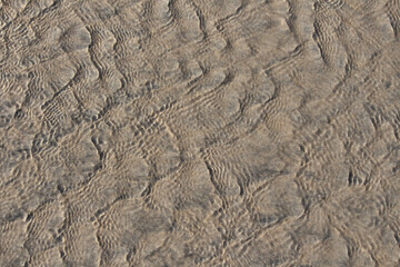 waves water washing over natural sand texture at the beach on the coast