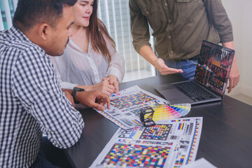 Crop image of worker checking print quality of media graphics proof print and color tone in...