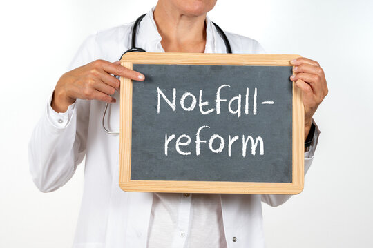 &Auml;rztin zeigt auf eine Tafel auf der Notfallreform steht