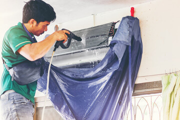 Technician cleaning the home air conditioner, spraying water for cleaning air conditioner at home....