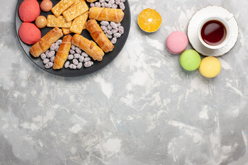 top view yummy cakes with crackers french macarons and cup of tea on the grey-white desk cake biscuit cookies sugar sweet pie