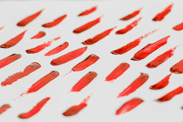 Smears of red cosmetic lipstick on a light background.