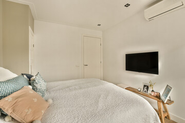 a bedroom with a tv on the wall and pillows on the bed in front of the television is mounted to the wall