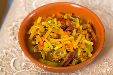 Vegetables stewed in spices with meat and garlic on a laid table.