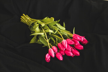 A bouquet of pink flowers sewn on black stylish linen.