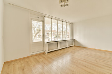 an empty room with white walls and wood flooring, there is a window looking out to the street outside