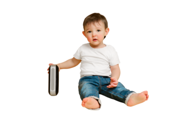 Toddler baby plays with a wireless music speaker on a studio isolated on a white background. Happy child in a white t-shirt and blue jeans listens to music in an audio speaker, copy space