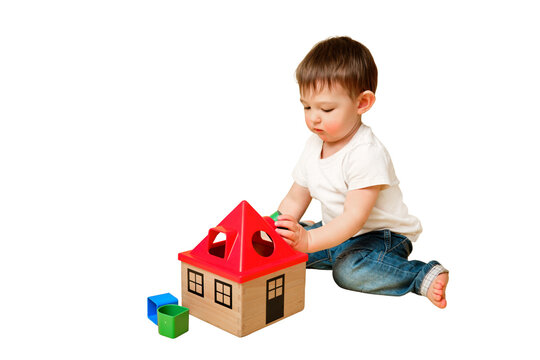 Toddler baby is playing sorter logic educational games with geometric shapes on a studio isolated on a white background. Happy child play with educational toy house. Kid aged one year four months