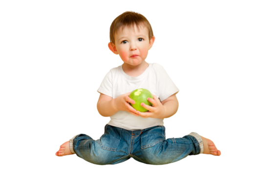 Toddler baby eats a sour apple on a studio isolated on a white background, surprised face. Child with a sour face in a white t-shirt and blue jeans. Kid aged one year and four months