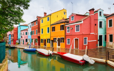 Fototapeta na wymiar Colorful houses and boats on the island of Burano, Venice, Italy.. Is an island in the Venetian Lagoon and is known for its lace work and brightly colored homes. Famous travel destination.