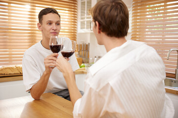 LGBT gay couple talking with boyfriend and drinking wine in dining room