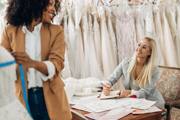 Two women work together in a bridal salon as a tailor and a designer.