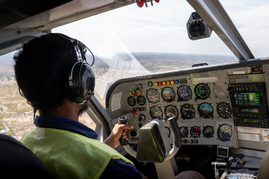 Pilot in Warnweste beherrscht die Cockpitinstrumente einer Gippsland GA-8 Airvan Propellerflugzeug / Kleinflugzeug &uuml;ber Botswana, Afrika