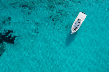 A yacht floating on the beautiful blue waters of Formentera, with a couple lying down and resting on board.