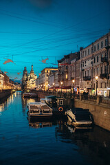 Canal embankment in the city in the evening. Bridges and beautiful buildings. Canal and pleasure boats and boats.