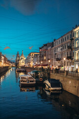Naklejka premium Canal embankment in the city in the evening. Bridges and beautiful buildings. Canal and pleasure boats and boats.