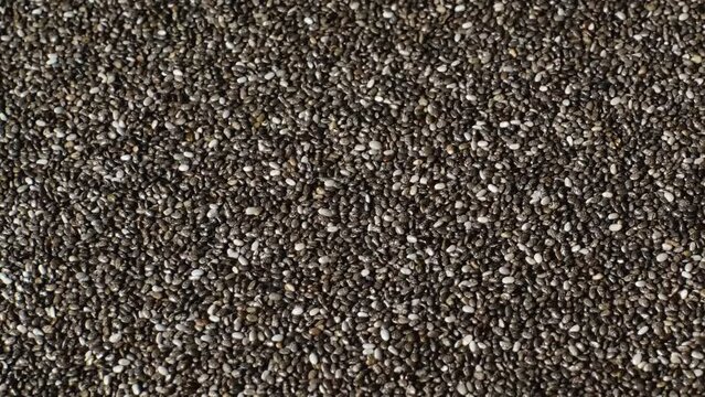 Slow motion of beautiful natural dried chia seeds rotating on a plate. Close-up of organic black and white Salvia Hispanica seeds. Superfood rich in Omega 3 fatty acids. Healthy lifestyle concept.