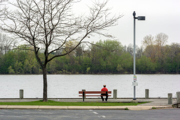 A Man Sitting On A Bench Looking Out At The River
