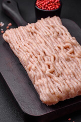 Fresh minced chicken with salt, spices and herbs on a wooden cutting board