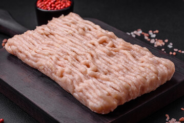 Fresh minced chicken with salt, spices and herbs on a wooden cutting board