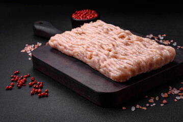 Fresh minced chicken with salt, spices and herbs on a wooden cutting board