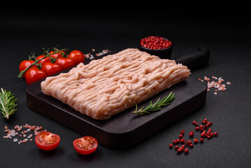 Fresh minced chicken with salt, spices and herbs on a wooden cutting board